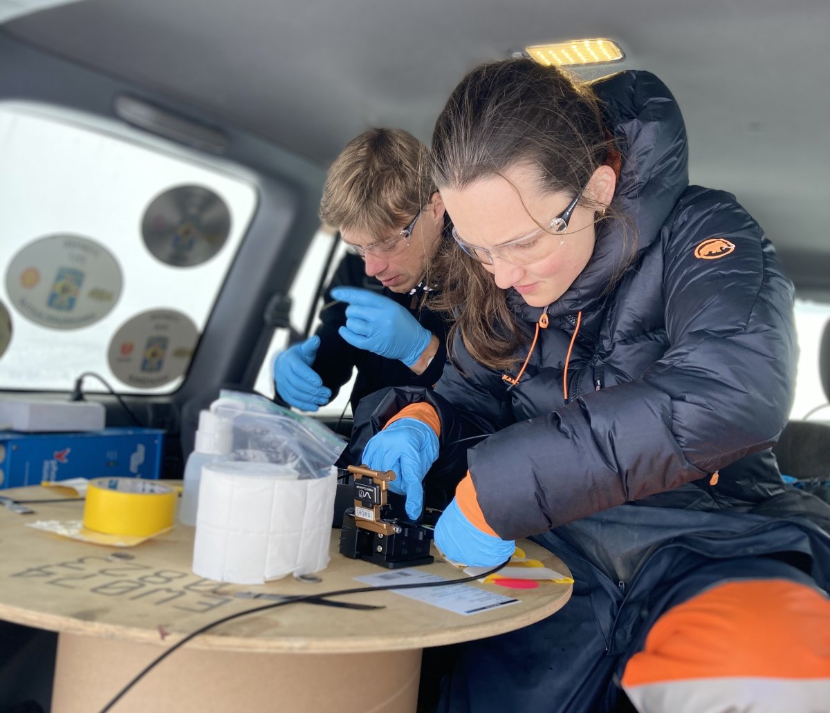 Sara hard at work splicing optic fibres in an improvised lab, on the glacier in the back of a Jeep.